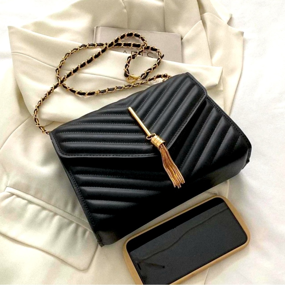 Black quilted crossbody bag with gold chain and tassel, detachable straps
